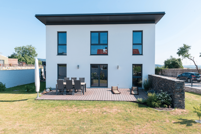 HARTL HAUS Holzindustrie zeigt ein schlicht modernes Fertighaus mit Pultdach und großer Terrasse.