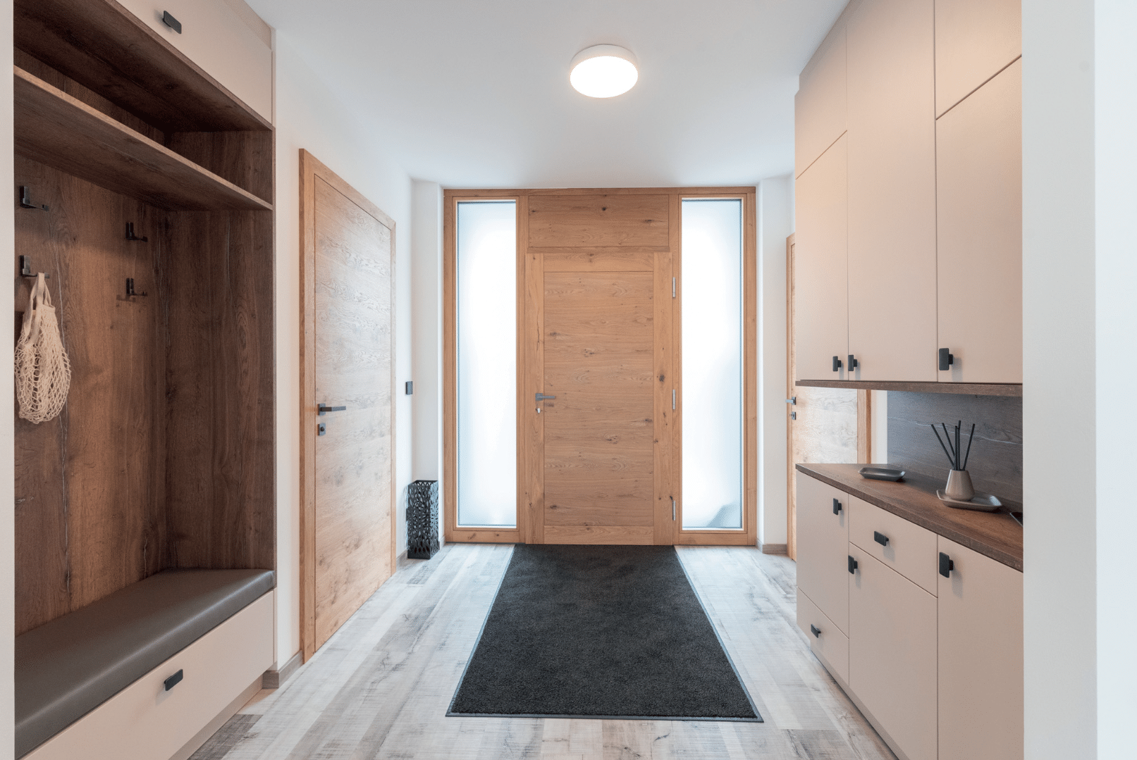 Hartl Haus zeigt einen geräumigen Eingangsbereich mit Holzboden, Einbauschränken, eingepasster Garderobe und einer imposanten Eingangstür aus Holz.