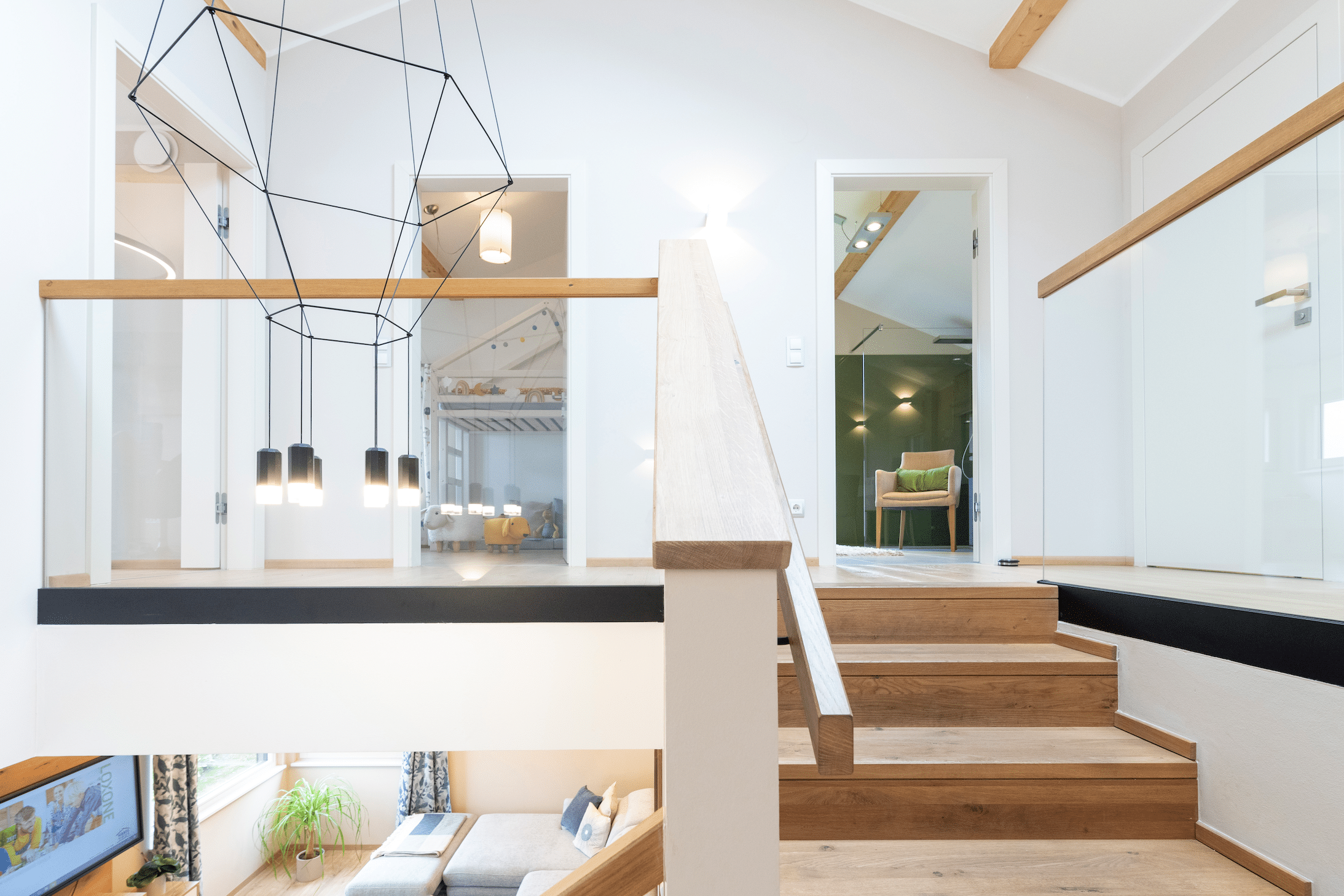 Hartl Haus zeigt ein Treppenhaus in einem modernen Haus mit Holztreppen, Glasgeländer und einem sehr modern konstruierten Lampenschirm.