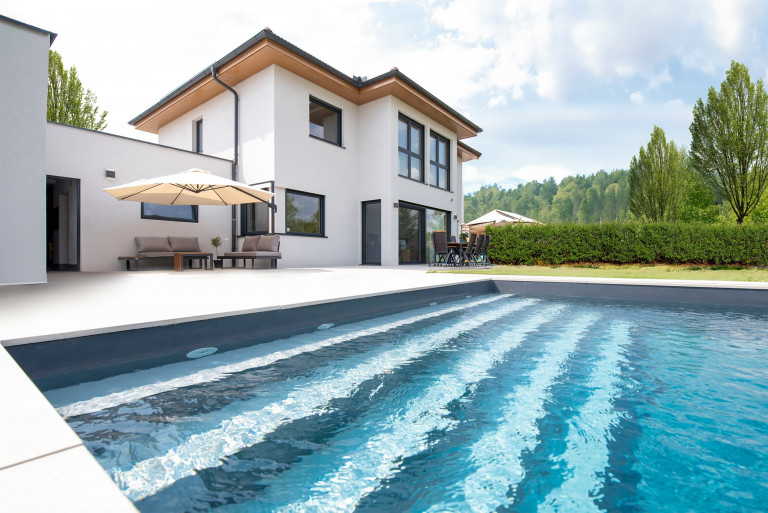 Großzügiges Wohnhaus mit Satteldach, weitläufiger Terrasse mit integriertem Pool und Loungemöbel von Hartl Haus.