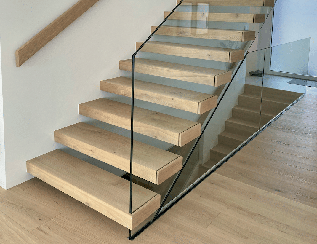 Die modernen und massgefertigten Treppen von Hausjell, Purrer & Stockinger fügen sich perfekt mit dem Glasgeländer in den Wohnbereich ein.