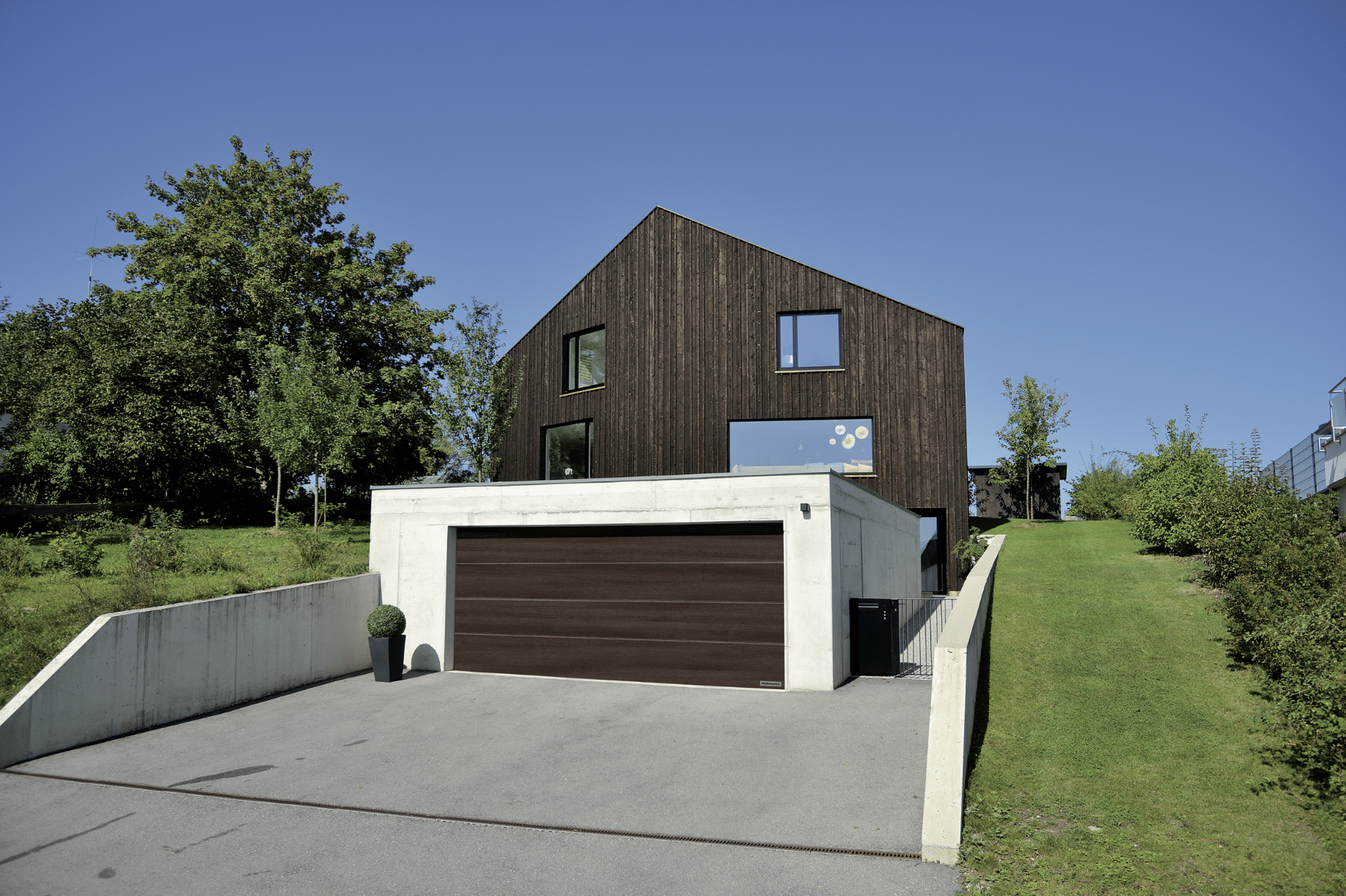 Einfamilienhaus mit Holzfassade und passendem Doppelgaragentor von HÖRMANN.