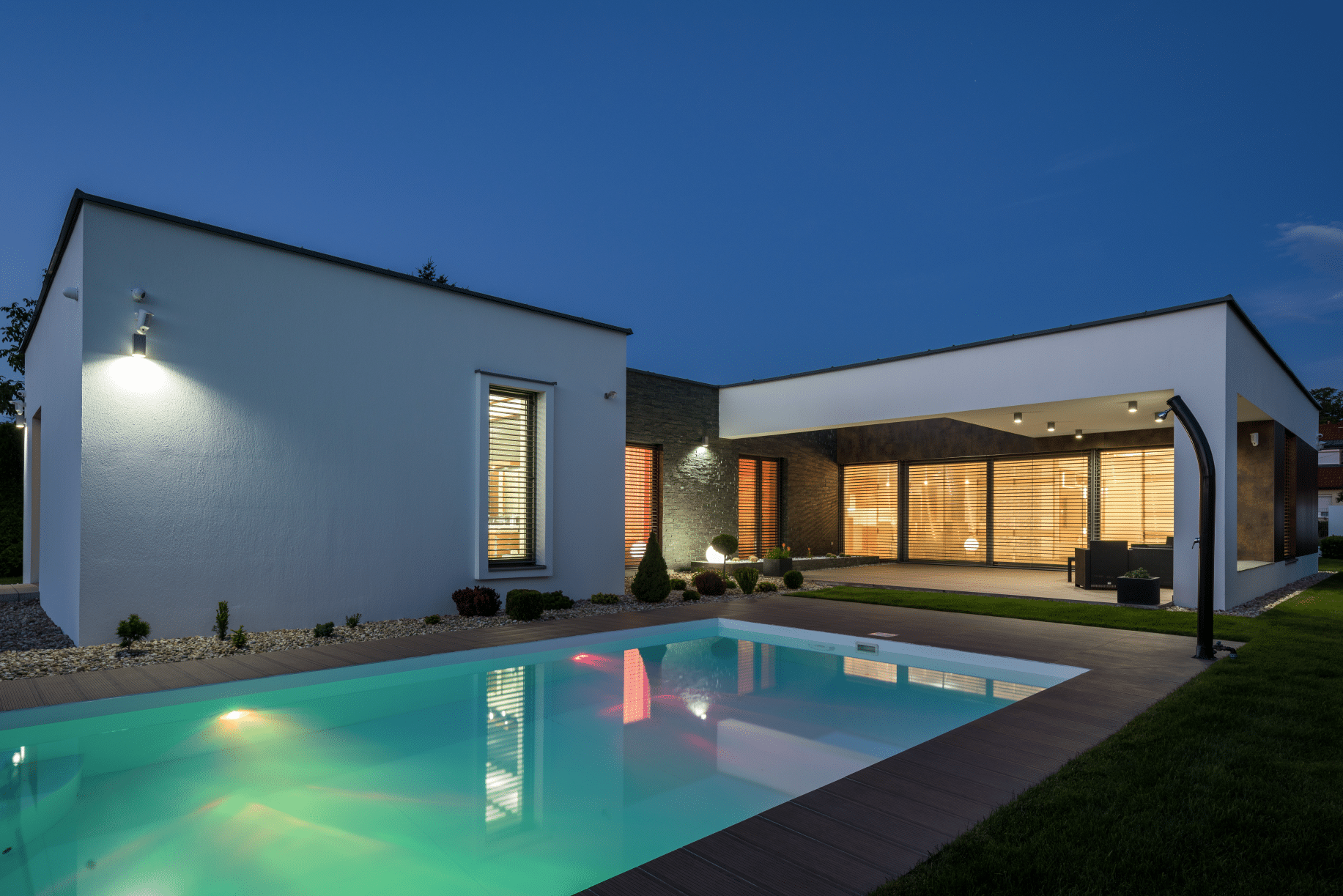 Modernes Smart-Home im Bauhaus-Stil mit Flachdach, beleuchtetem Pool, großer Terrasse sowie deckenhohen Fenstern und Schiebe-Terrassentüren von Internorm.