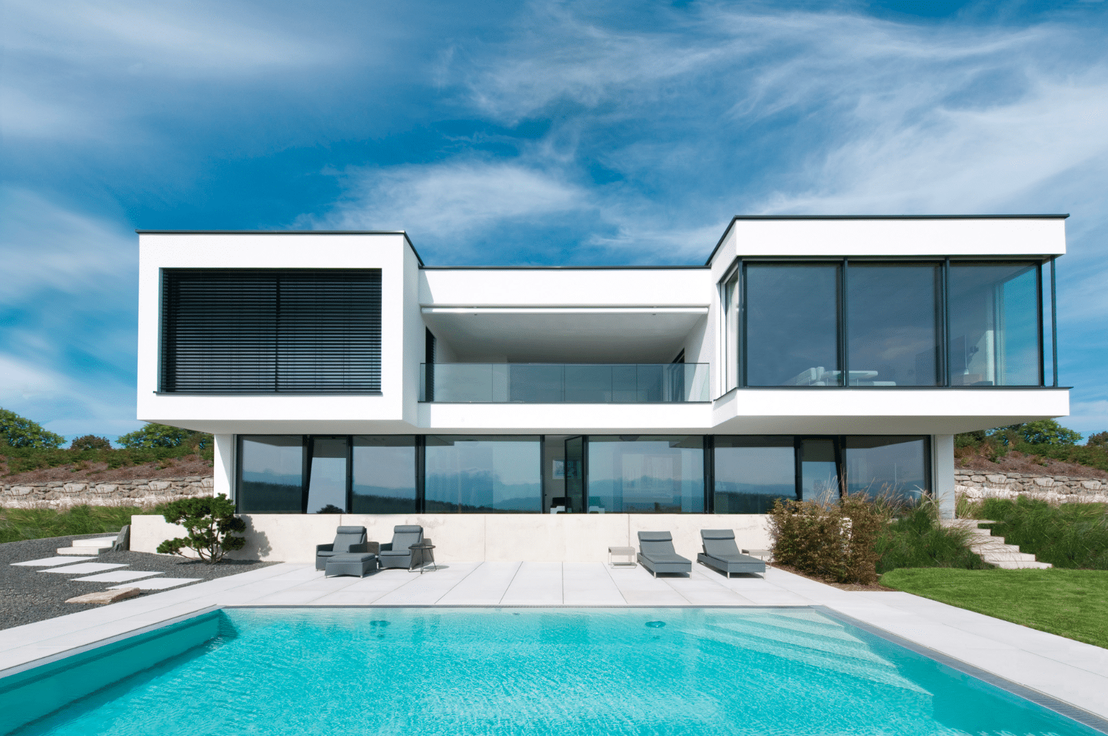 Internorm zeigt ein Architektenhaus mit großen Fenstern, Glasfronten und einem Garten mit Terrasse und Pool.