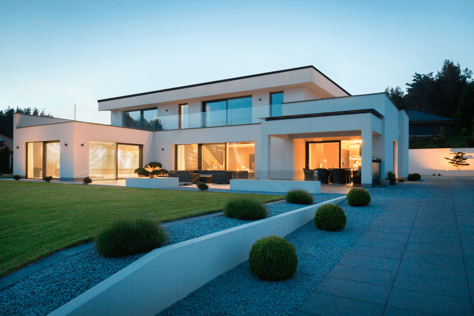 Internorm zeigt ein Architektenhaus mit Flachdach, großen Fenstern, Glasfronten und einer langen, breiten Einfahrt.