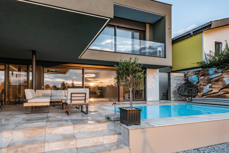 Großflächige Terrasse mit Pool, Marmor-Bodenfliesen und großen Fensterflächen und Glasschiebetür von Internorm.