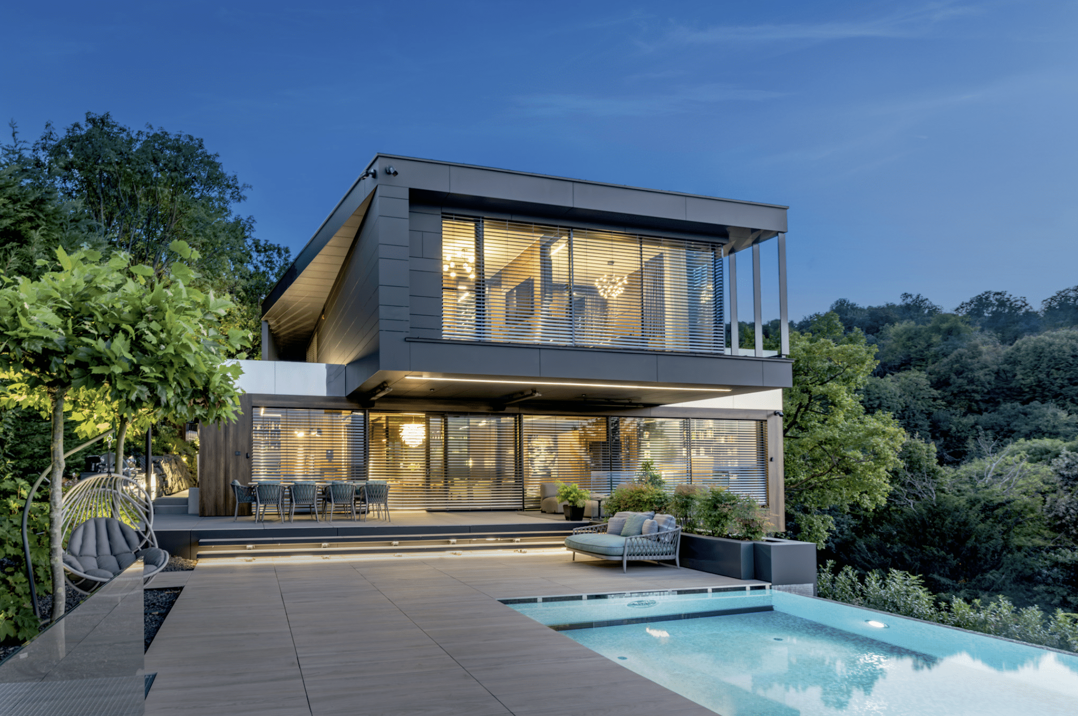 Internorm präsentiert eine sehr moderne, zweistöckige Villa mit Holzverbau, Terrasse,  und Pool umgeben von Wald.