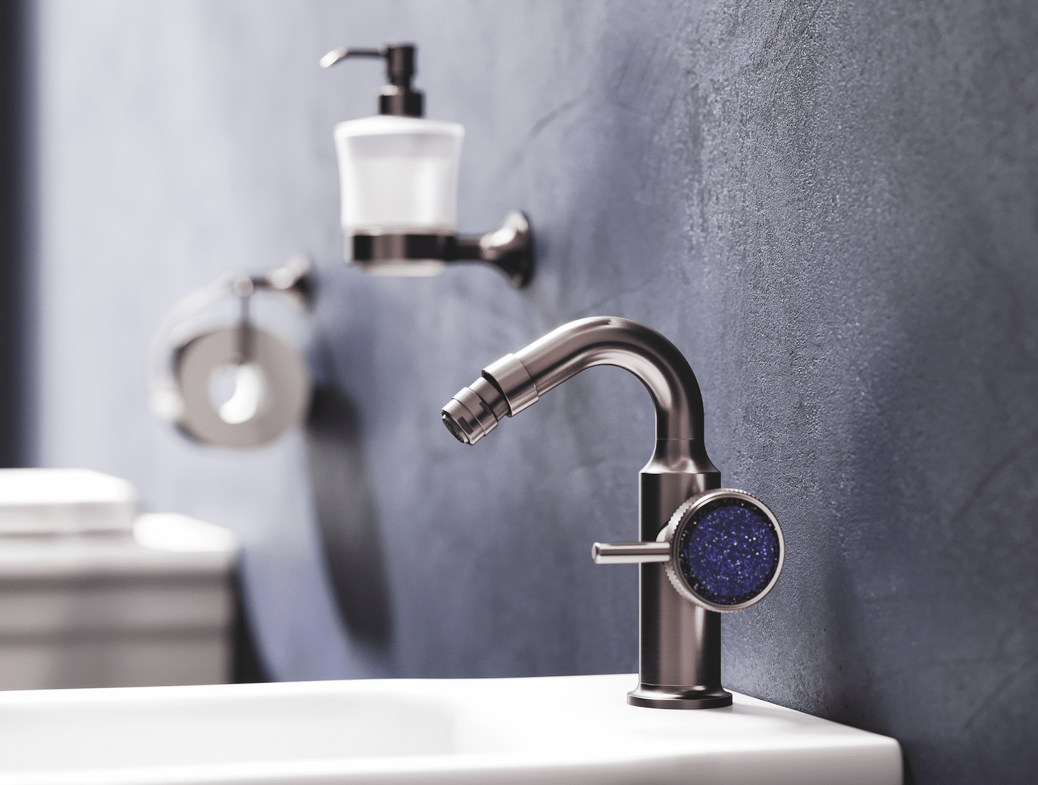 Die Bidet-Armatur aus der „Valencia“-Kollektion in Nerz matt. Am Hebelgriff funkelt der kostbare, blaue Aventurin. Im Hintergrund machen als hochwertige, passende Accessoires der Lotionspender und Papierhalter als Wandmodelle auf sich aufmerksam.