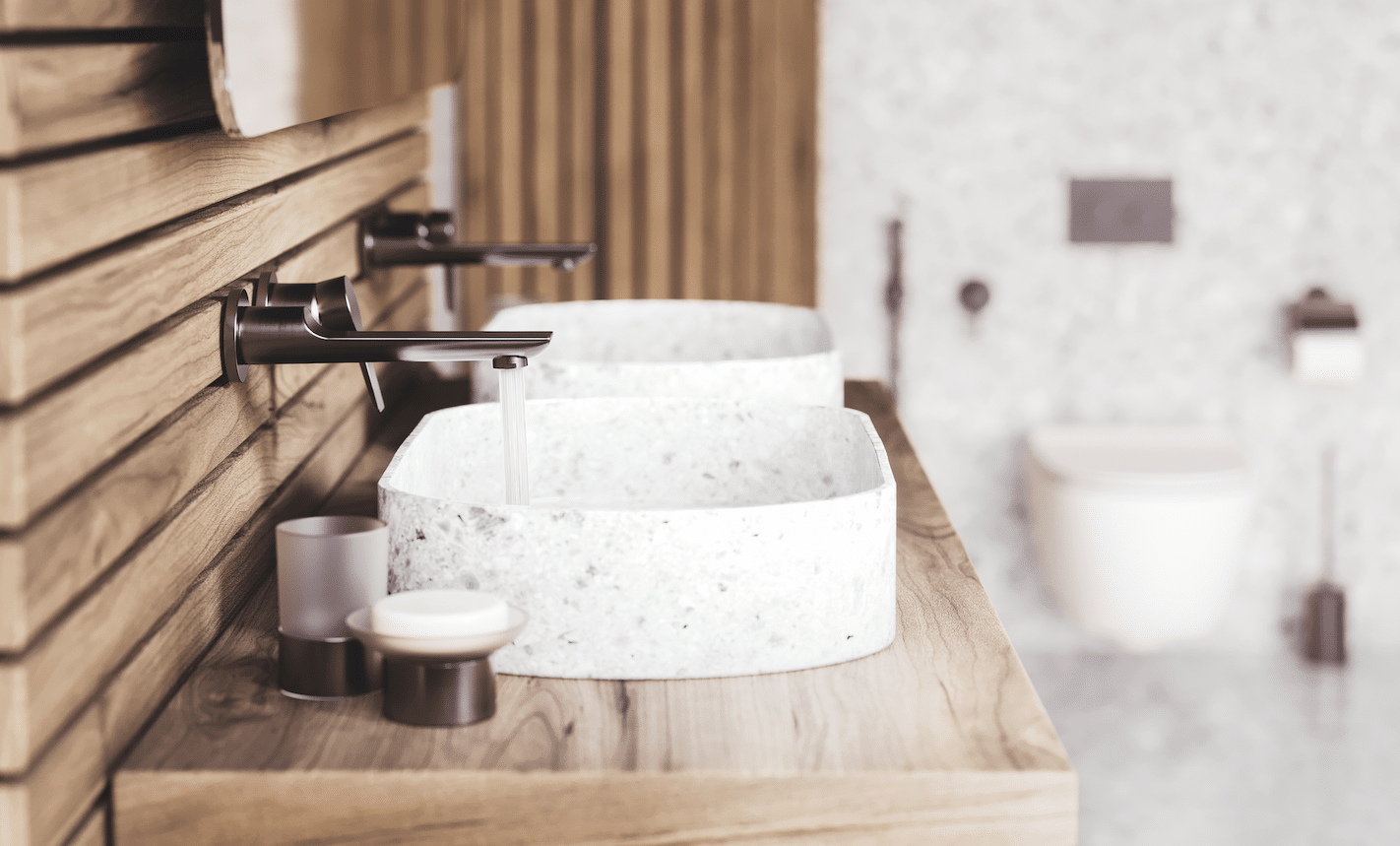 Jörger zeigt einen Doppelwaschtisch mit gesprenkeltem Waschbecken und Waschtisch aus Holz mit Armaturen, Mischbatterie und Halterungen in Nerz matt aus der Serie Exal.