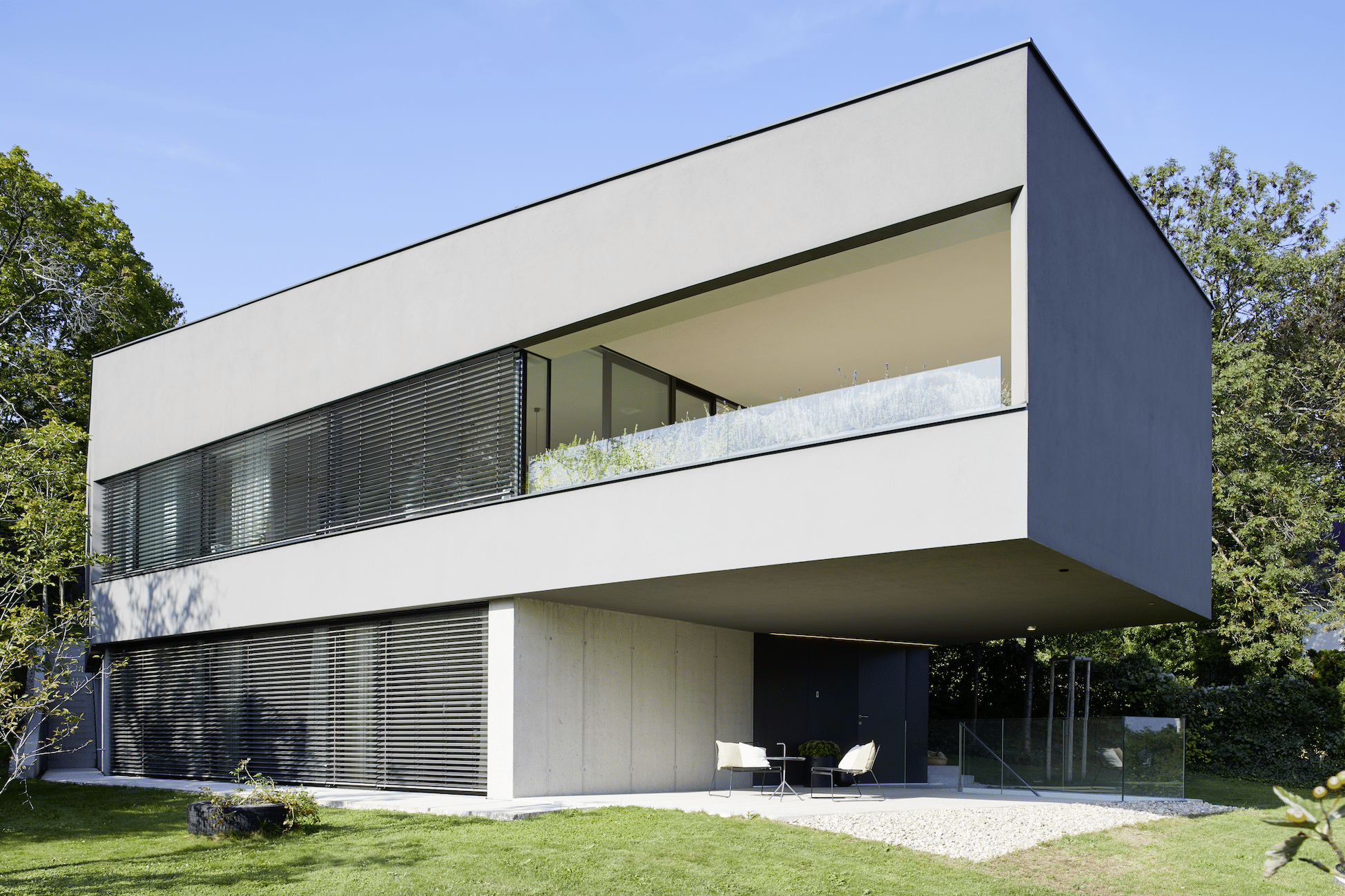 Modernes Einfamilienhaus mit überdachter Terrasse und beschatteten Fensterflächen von Josko.