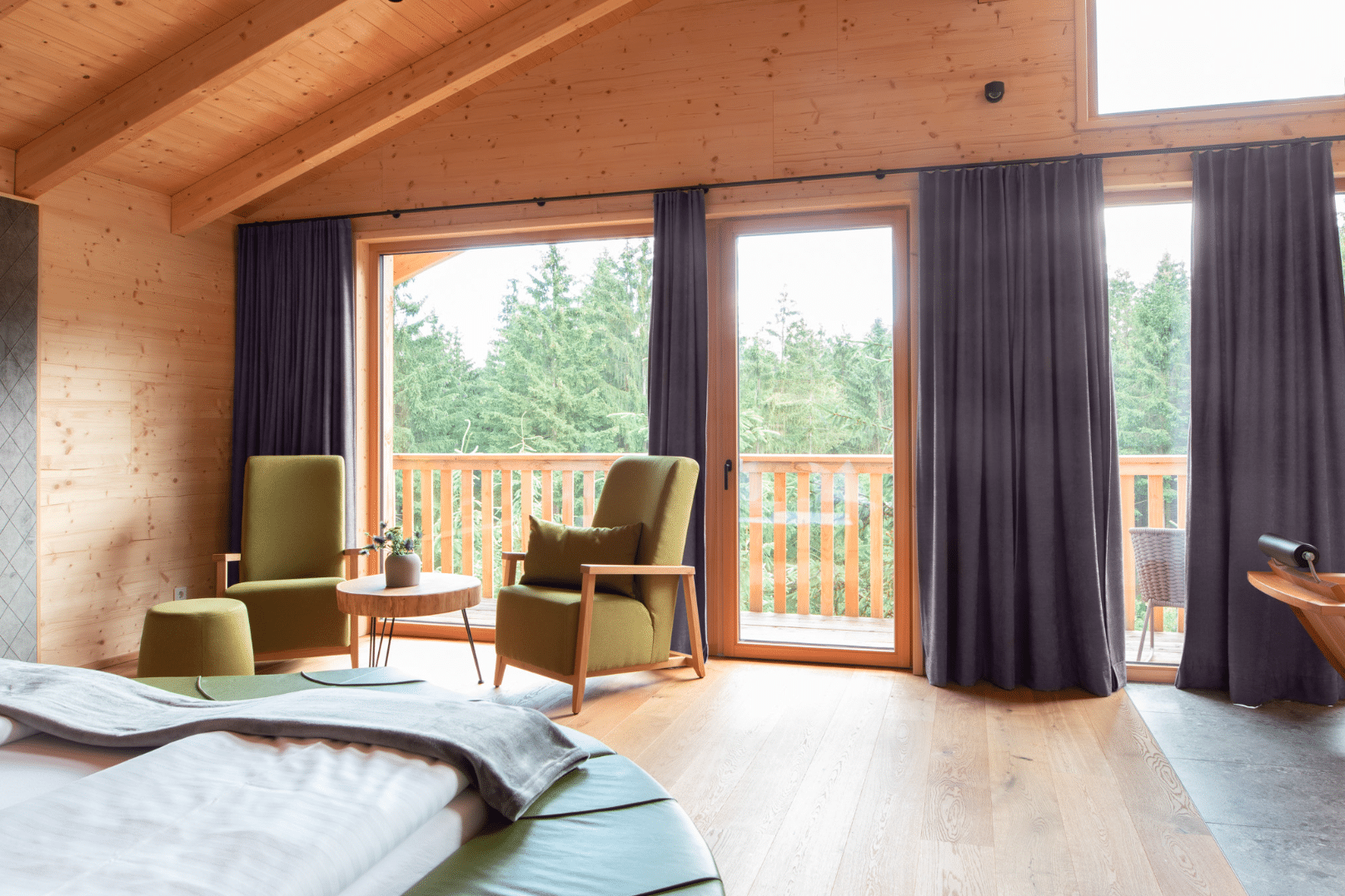 Schlafzimmer mit Wandverkleidung aus Holz, großen, deckenhohen Fenstern und einer Terrassentür von Josko.