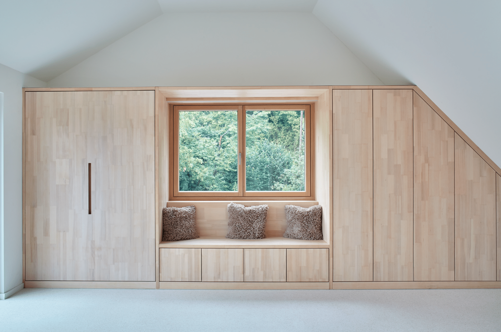 Innenraum mit einem Einbauschrank aus Holz und einer Sitzbank, angepasst an ein Doppelfenster von Josko.