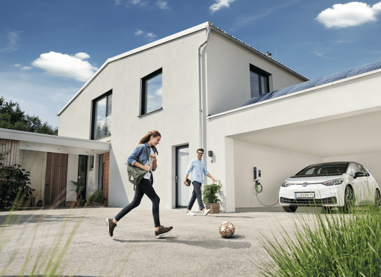 KEBA zeigt ein weisses Einfamilienhaus mit Carport in dem ein Auto an der Wallbox aufgeladen wird.