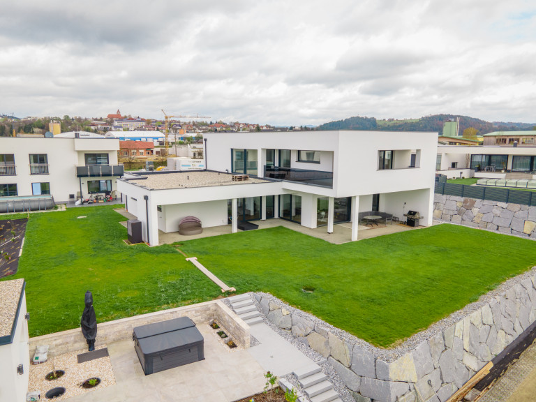 Moderne kubische Villa mit bodentiefen Glasfenstern und einem überdachten Außenbereich von B. Kern Baugesellschaft.