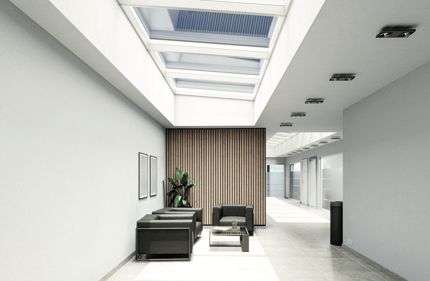 Lamilux zeigt einen Gang in einem Bürogebäude mit einem Wartebereich, schwarzen Lederstühlen und einem Panoramadach für den Einfall von Tageslicht.