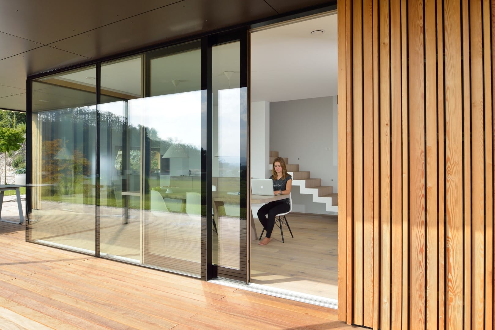Lichtdurchfluteter Wohnraum zur Terrasse hin ausgestattet mit stylischen Schiebetüren mit schmalem, schwarzem Rahmen von M SORA.
