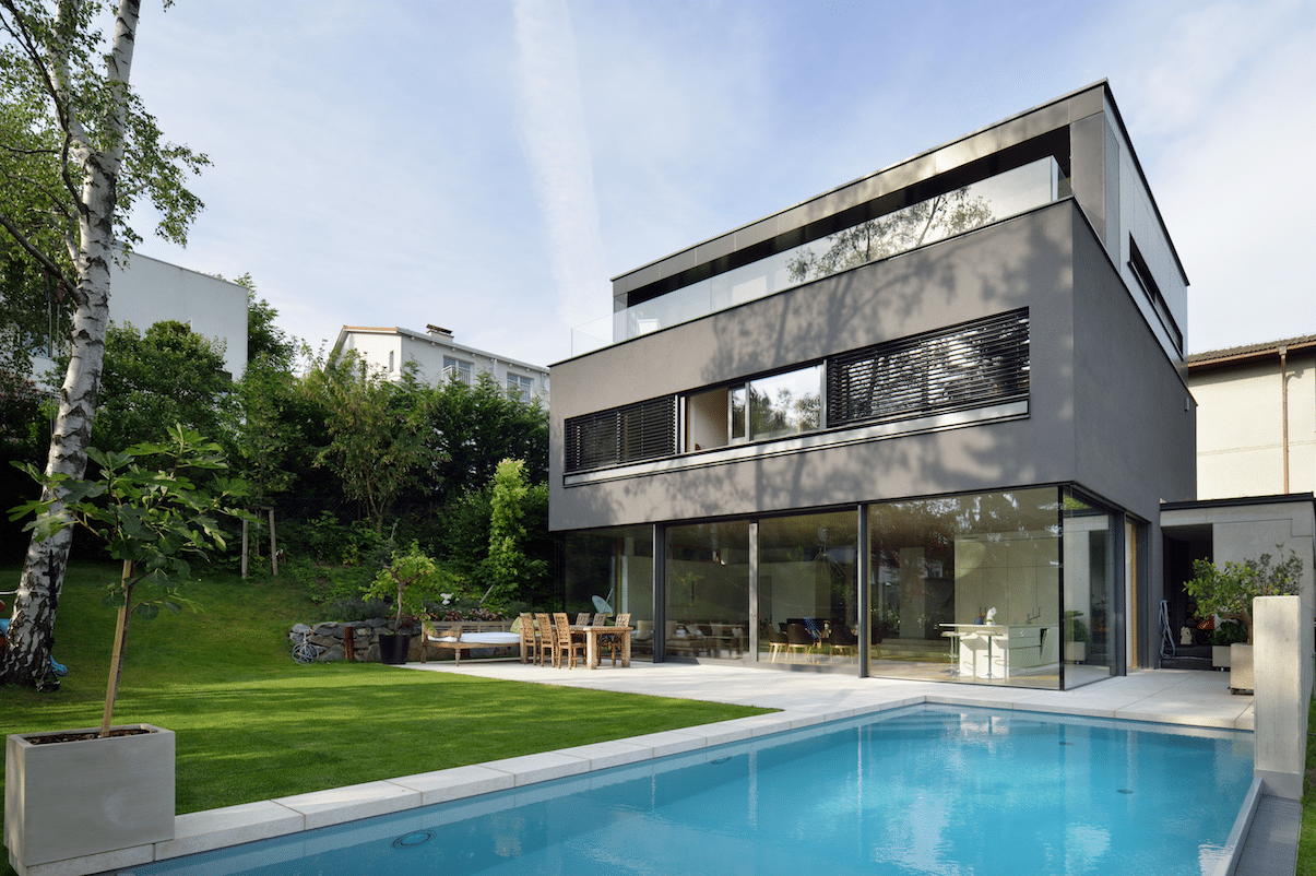 Anthrazitfarbenes Architektenhaus mit Flachdach und Pool präsentiert sich mit Fenster und Ganzglaslösungen von M SORA.