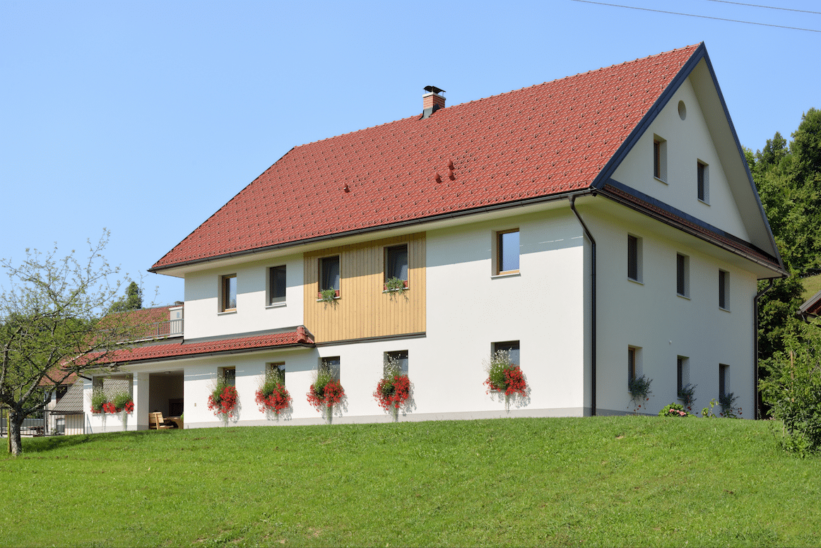 Großes, traditionelles Landhaus mit Balkonblumen und zahlreichen Fenstern von M SORA.