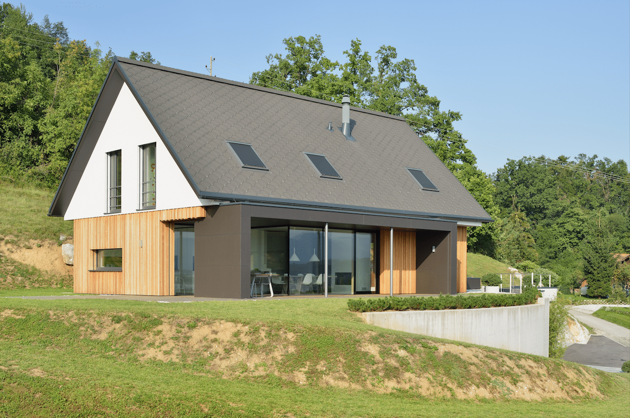 Modernes Haus, gebaut am Hang, ausgestattet mit Holzfassade, M SORA Fenster, Dachfenster, Vollverglasung und deckenhohen Schiebetüren zur Terrasse hin.