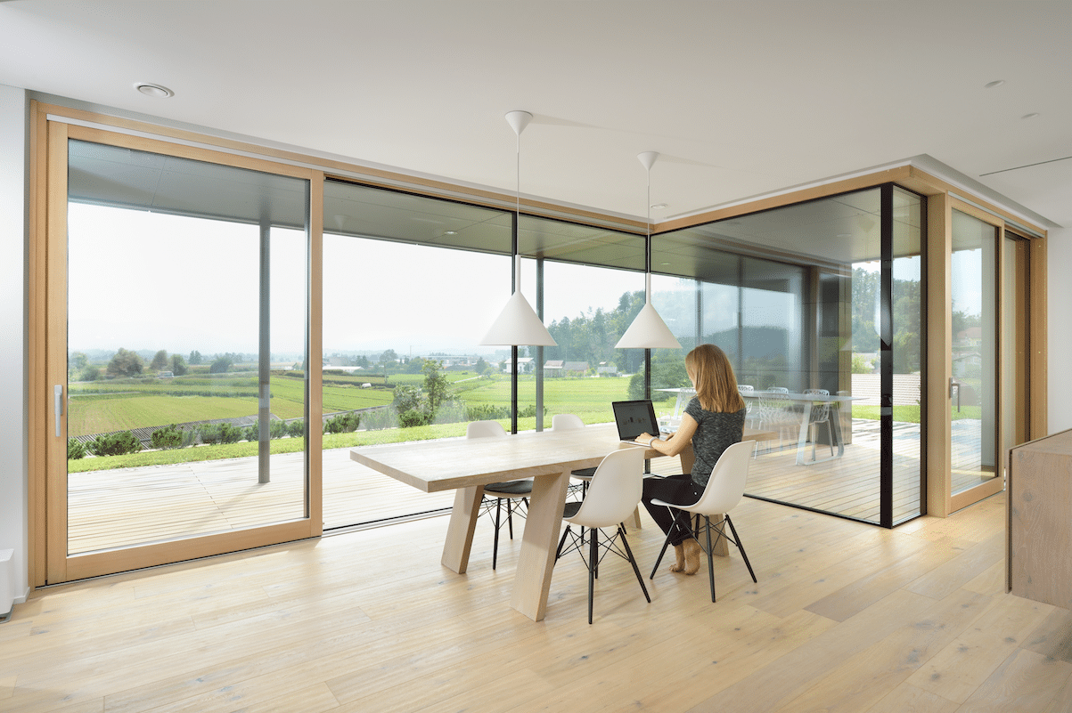 Geräumiges, helles Esszimmer, umfunktioniert zum Home Office, ausgestattet mit Vollverglasung zur Terrasse hin und deckenhohen Glasschiebetüren aus Holz-Alu von M SORA.