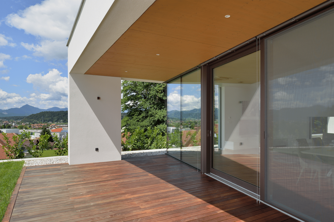 Überdachte Terrasse mit Holzboden, Spotleuchten und barrierefreien Glas-Schiebetüren von M SORA.