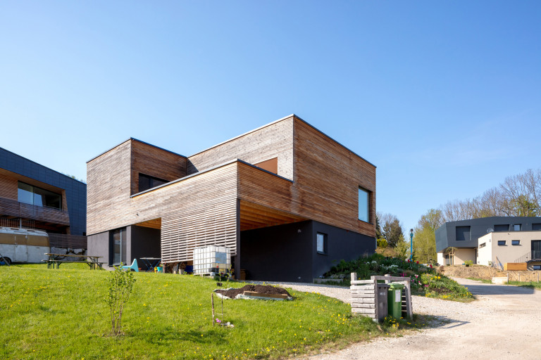 Modernes Architektenhaus mit Holzverkleidung, überdachtem Eingang und großzügigem Balkon sowie Fenstern und Türen der Firma Maderböck.