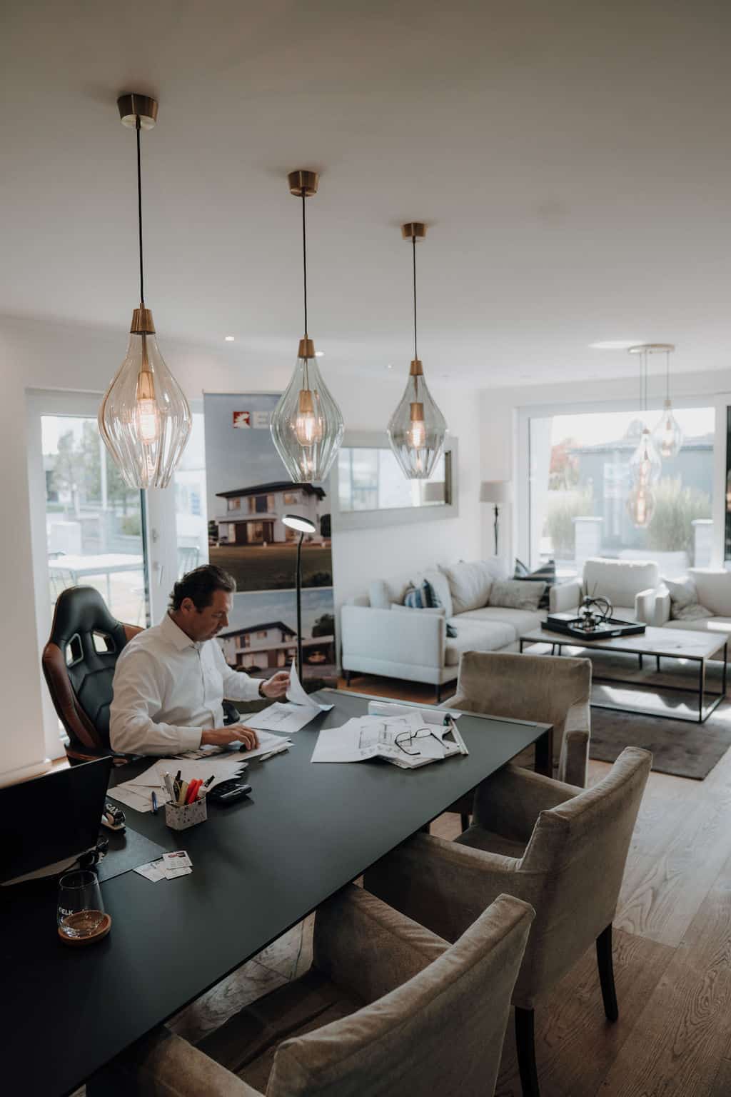 Im offenen Wohnraum eines Musterhauses werden am Esstisch Baupläne studiert.