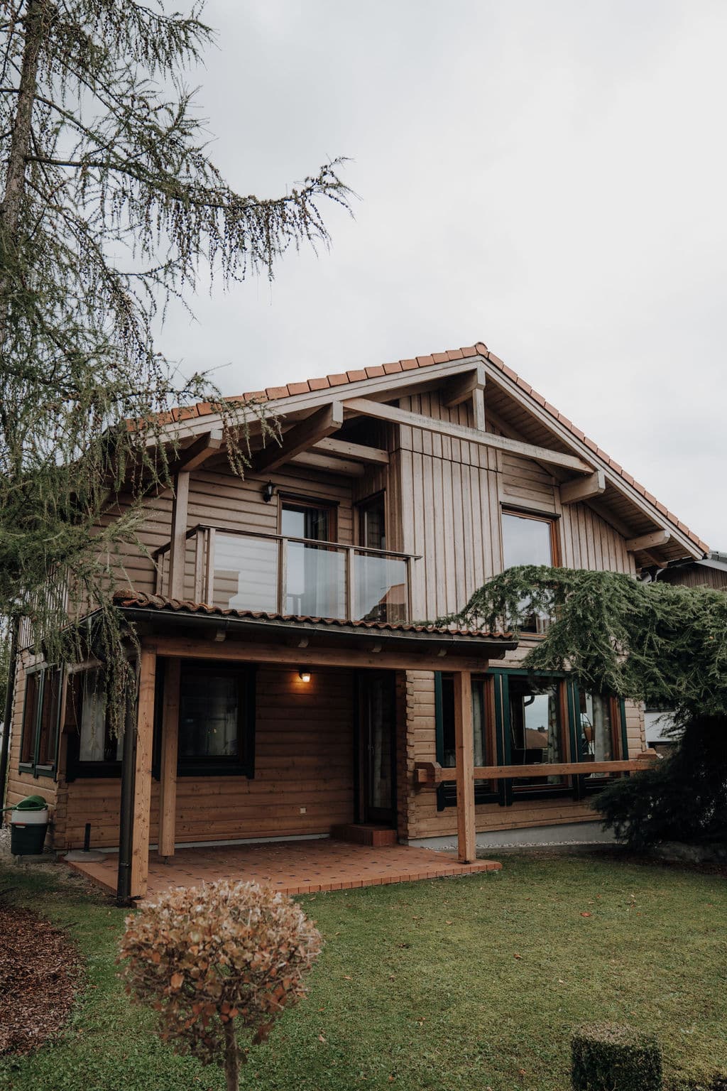 Musterhaus in Holzriegelbauweise mit überdachter Terrasse und Balkon mit Glasgeländer im Musterhauspark.