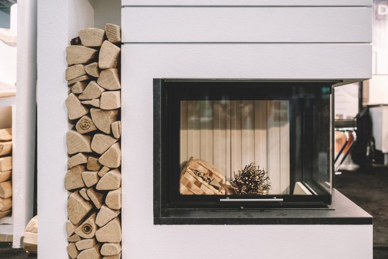 Moderner Kamin mit Sichtfenster und Holzlager auf der Baumesse Oberwart.