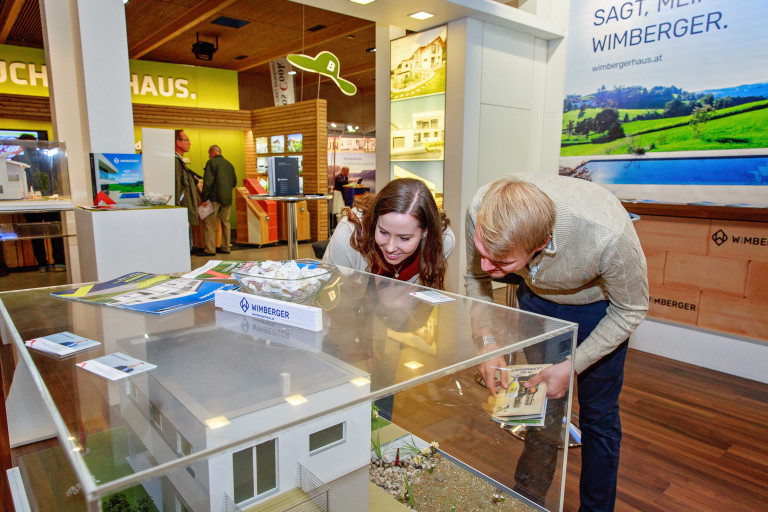 Besucher bestaunen ein Modellhaus unter Glas auf der Messe Wieselburg.