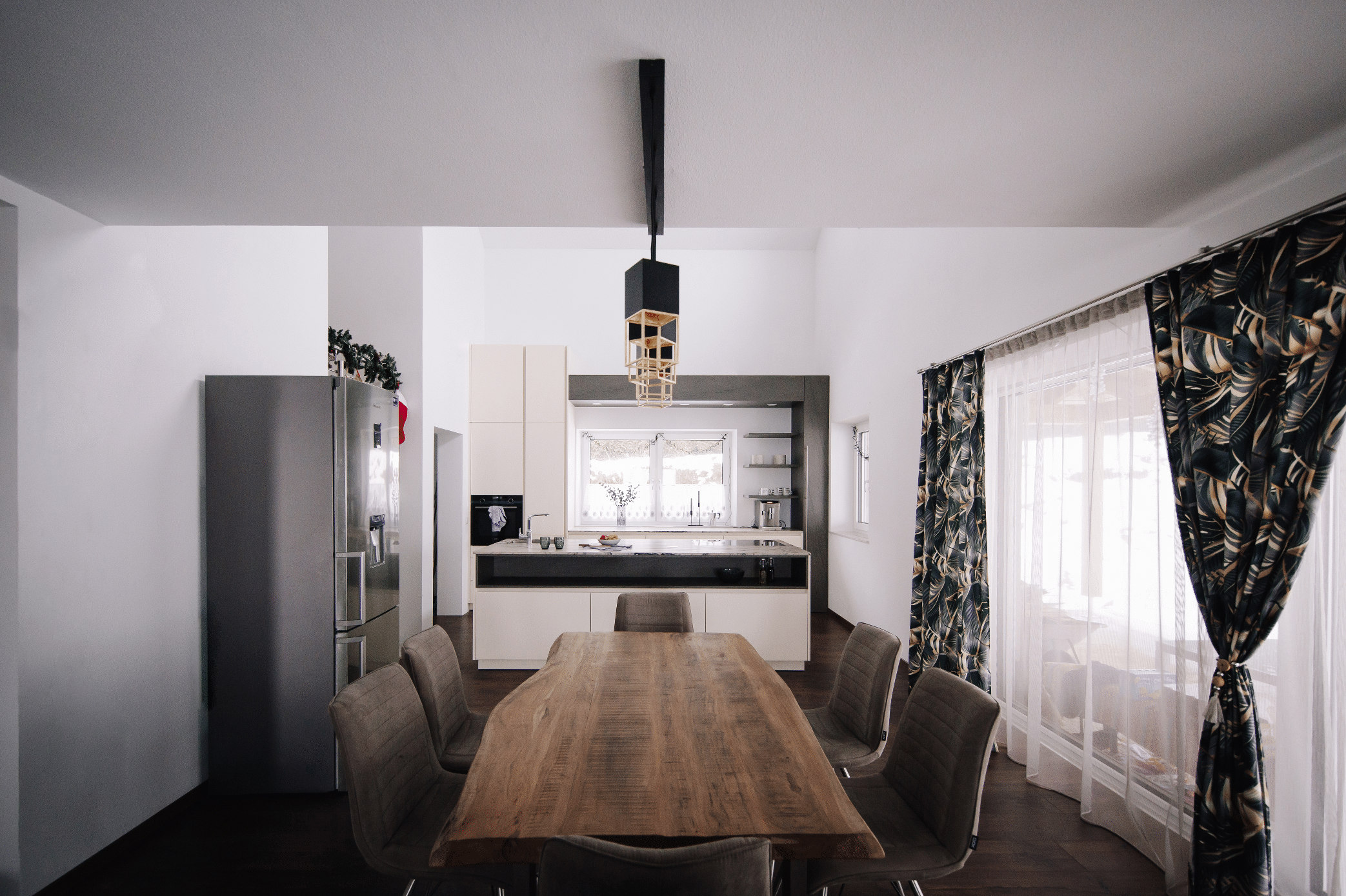 MF Interieur zeigt ein Esszimmer mit großem Holztisch und Lederstühlen in braun und eine kleine Küche mit weissen Fronten und schwarzen Akzenten.