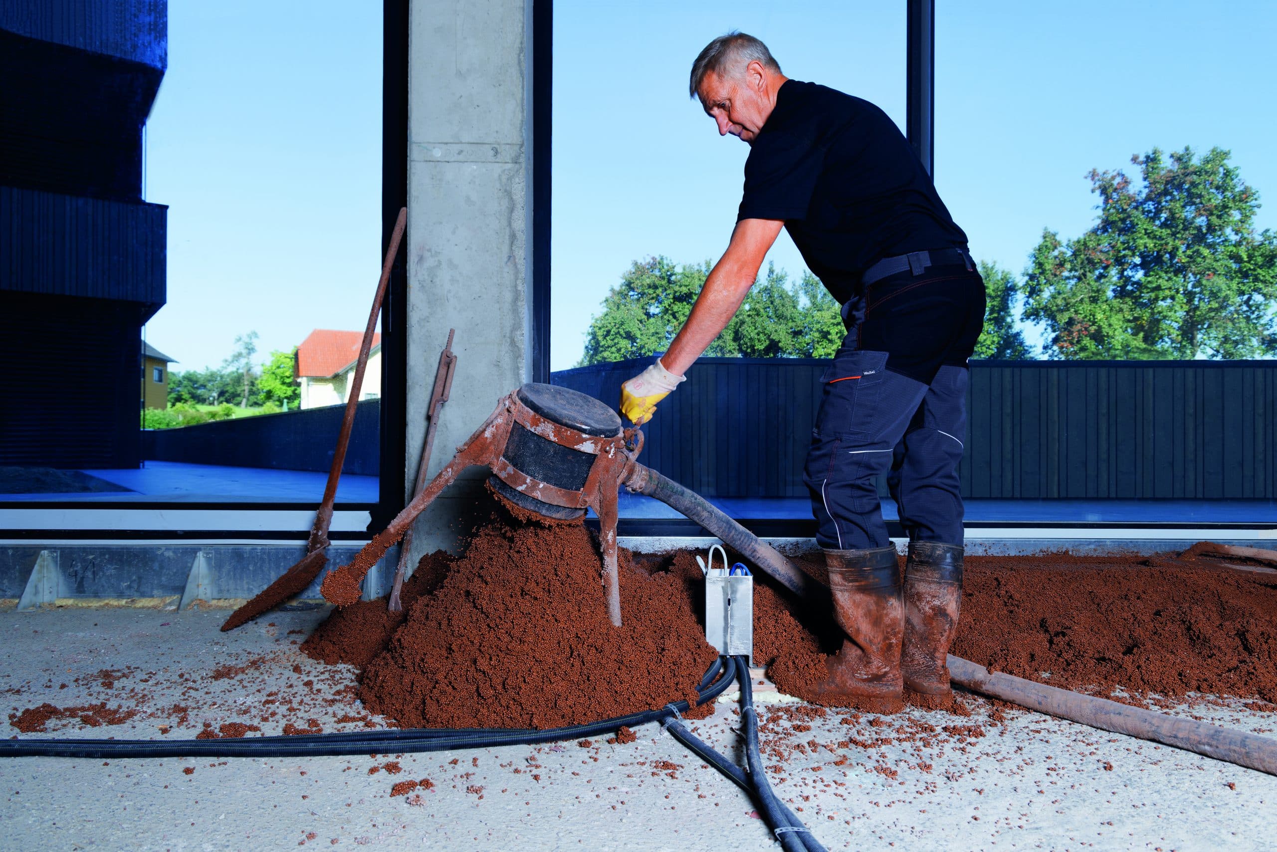 Arbeiter beim Fußbodenaufbau mit thermotec® in einem Raum mit bodentiefen Fenstern von thermotec®.