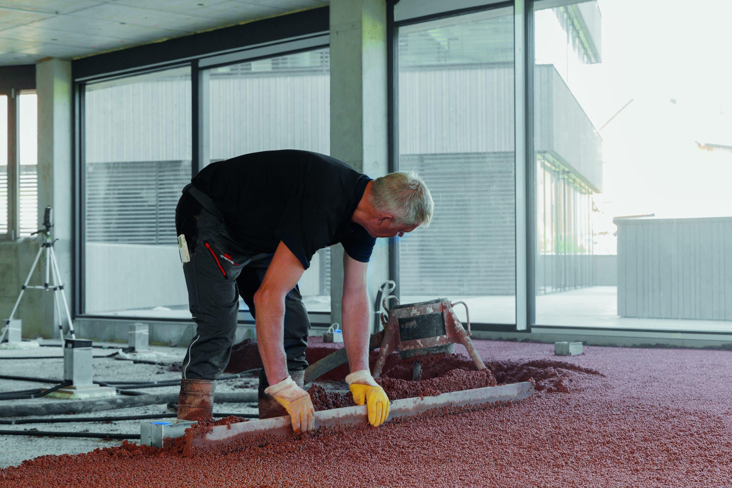 Arbeiter beim Aufbau einer Bodenplatte mit thermotec® in einem Raum mit bodentiefen Fenstern und Ganzglassystem von thermotec®.