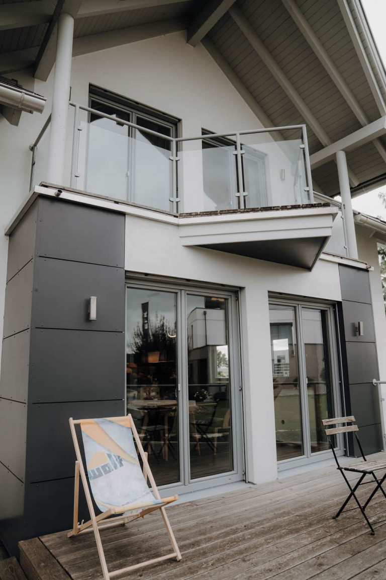 Musterhaus mit überdachtem Balkon mit Glasgeländer und großzügiger Terrasse im Musterhauspark.