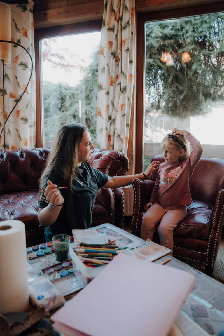 Fröhliches Kinderschminken im Wohnzimmer eines Musterhauses im Musterhauspark.