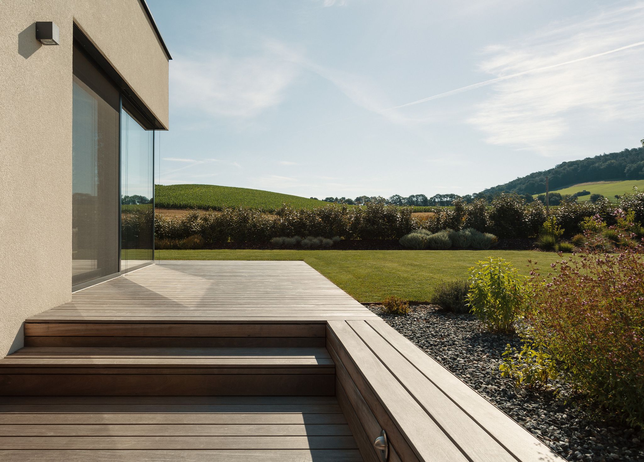 Nentwich zeigt auf diesem Foto eine Terrasse verbaut mit Holz über die man vom Haus in den bepflanzten Garten kommt.