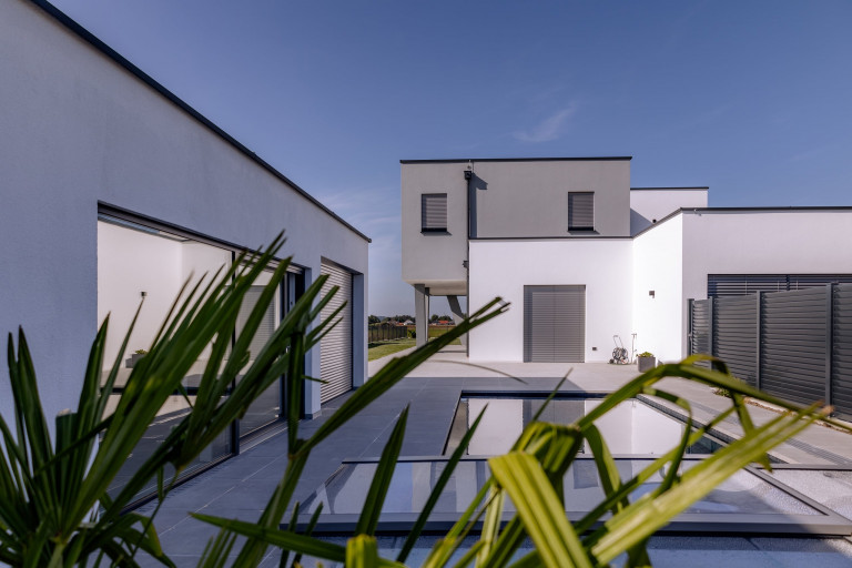 Modernes Flachdach-Wohnhaus mit Terrasse und Pool und zur Gänze geschlossenen silber Jalousien von Newo.