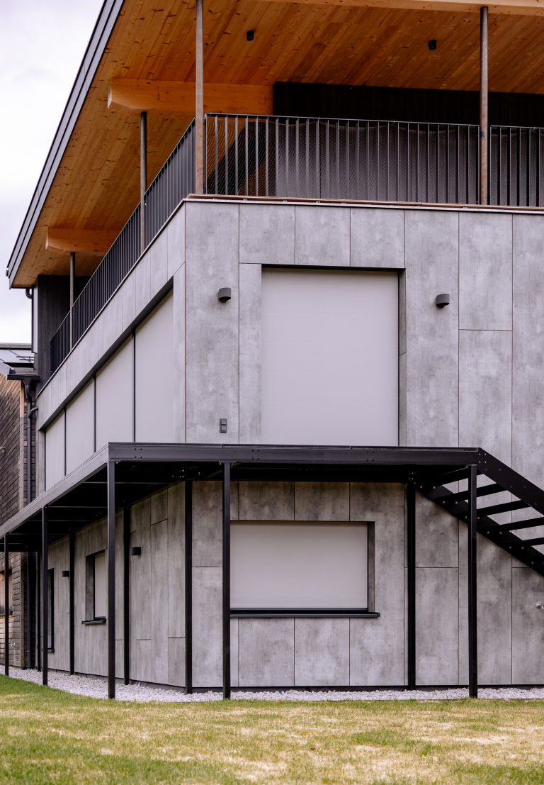 Modernes Wohnhaus mit Verkleidung aus Beton und Holz mit zur Gänze geschlossener grauer Textilscreen-Beschattung von Newo.