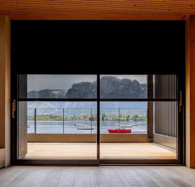 Große Glasfront mit Glasschiebetüre und textiler ZipTex Beschattung von Newo mit Blick auf Terrasse und See.