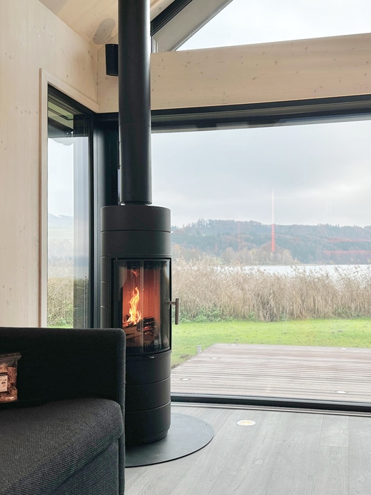 Runder Kamin in schwarz mit runder Ofentüre von Ofenmanufaktur Liebewein in einem modernen Holzhaus.