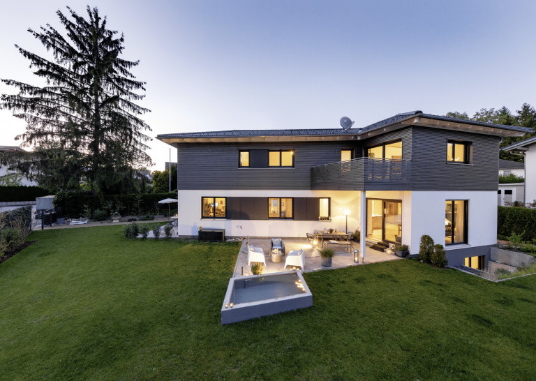 Haus "Starnberg" von Regnauer am Abend mit Gartenteich und großer Terrasse.