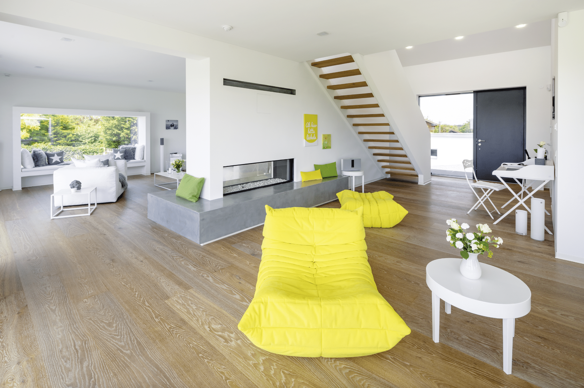 Offener Wohnraum mit moderner Treppe und knalligen Accessoires in einem Regnauer Fertighaus.