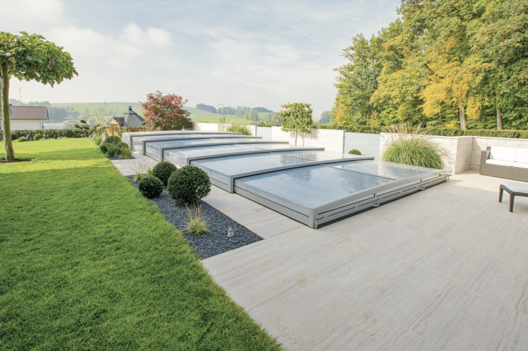 Friedrich Reitinger Schwimmbad und Wellness zeigt einen in den Boden eingelassenen, rechteckigen Pool mit Holzumrandung und einer gläsernen Poolabdeckung.