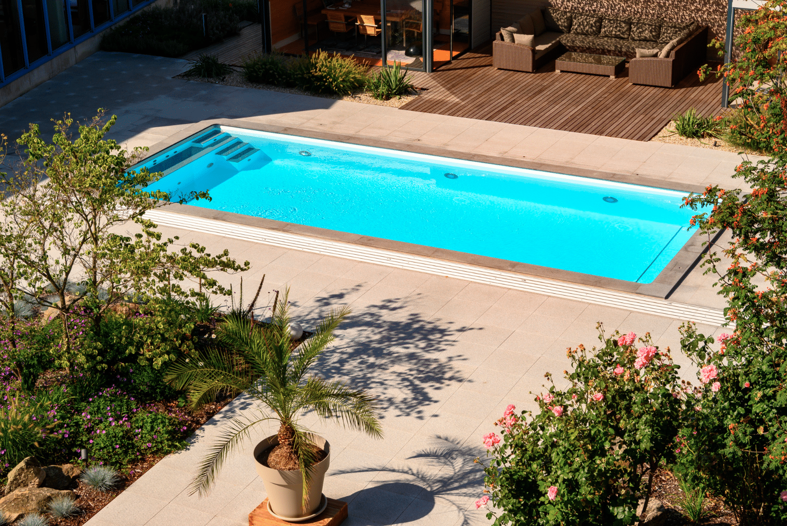 SAUNA-SCHWIMMBAD RUHA Stelzmüller zeigt einen Garten mit großem Swimmingpool und Terrasse.