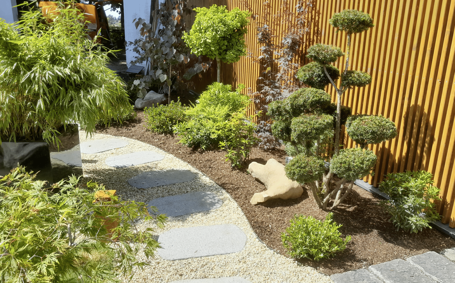 Gartenbau Schmid zeigt einen angelegten Weg mit verschiedenen Pflanzen und kleinen Bäumen an den Seiten.
