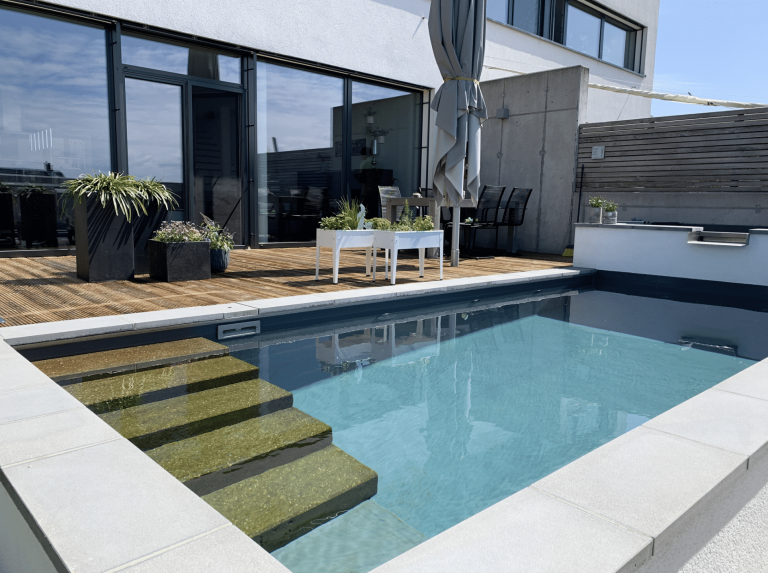 Gartenbau Schmid zeigt die sehr moderne Terrasse eines neuen Hauses und Pool mit Stufen.