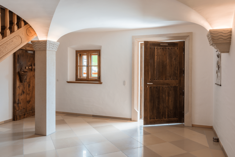 Silber Fenster zeigt den Eingangsbereich eines alten Stadthauses mit Gewölbe, einem kleinem Holzfenster und einer Holztür.