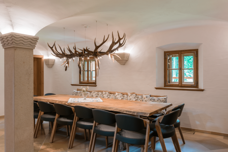 Silber Fenster zeigt ein Esszimmer in einem alten Haus mit Gewölbe, kleinen Holzfenstern, einem Holztisch und rustikalen Accessoires.