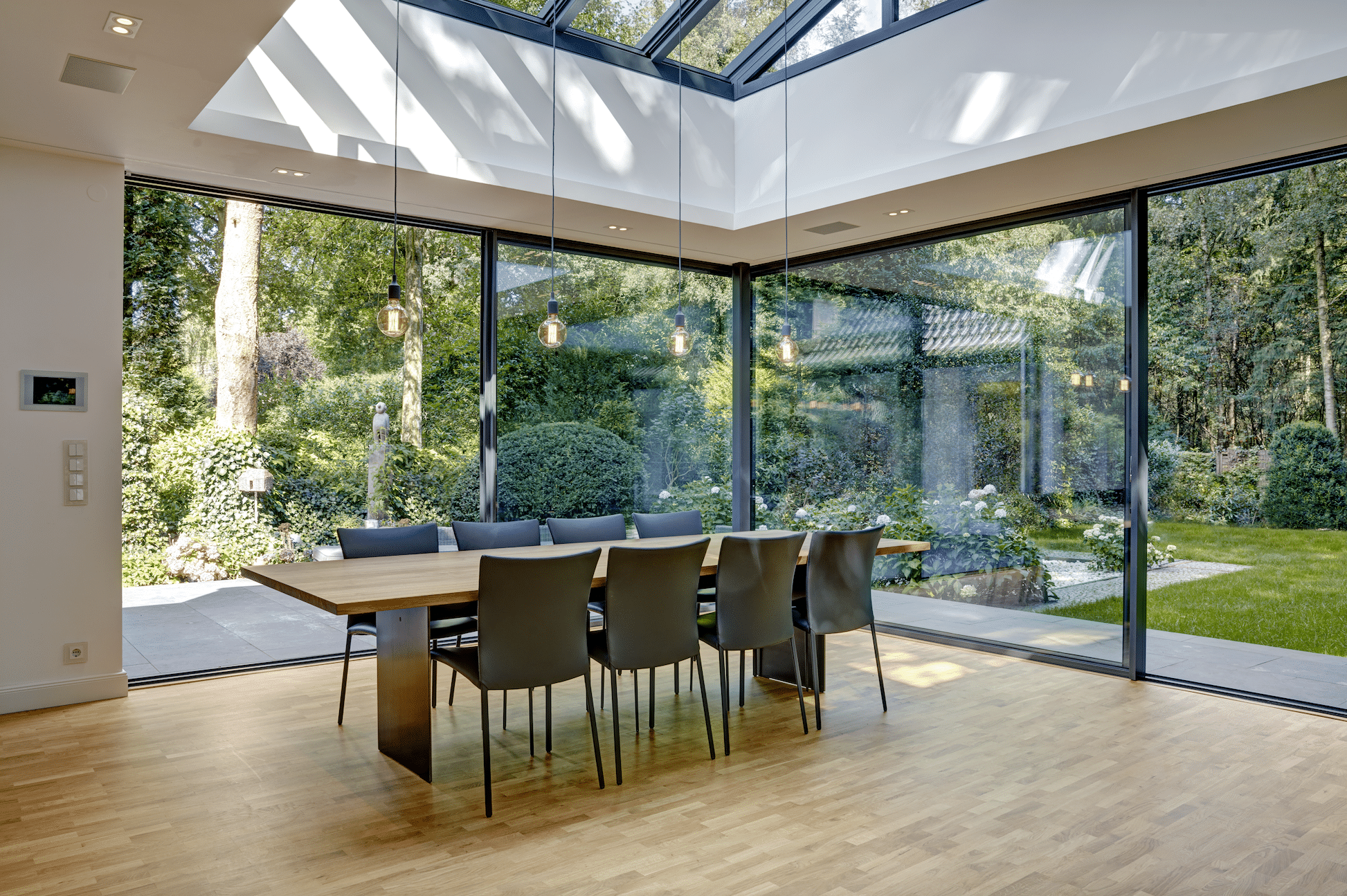Moderner Wintergarten mit Essbereich und großen Glas-Schiebetüren von Solarlux.
