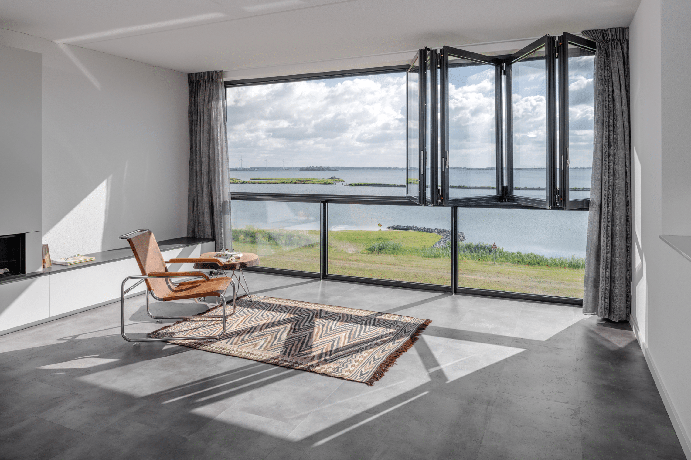 Wohnzimmer mit Panoramablick aufgrund einer Fixverglasung in Kombination mit der Glas-Faltwand Ecoline von Solarlux.